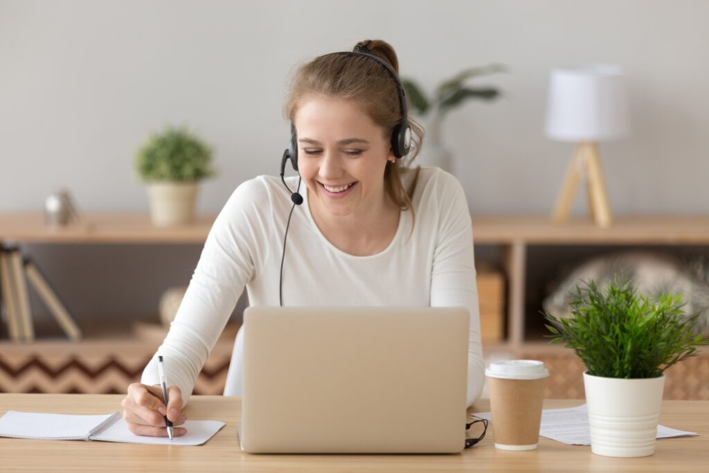 Image of a woman smiling in font of a laptop