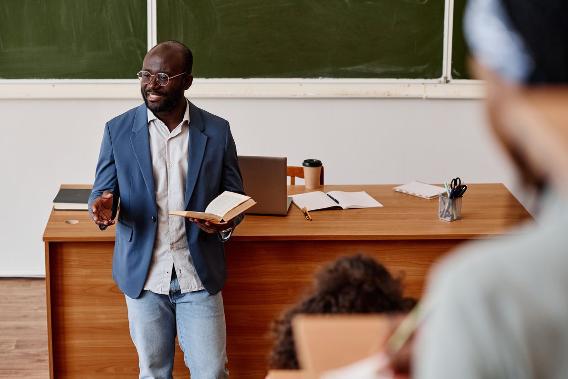 Teacher reading lecture at university African teacher standing with book and reading lecture for students at university